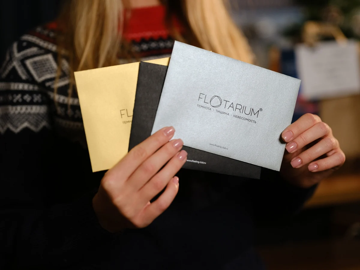 Гостья держит фирменные конверты FLOTARIUM для подарочных сертификатов